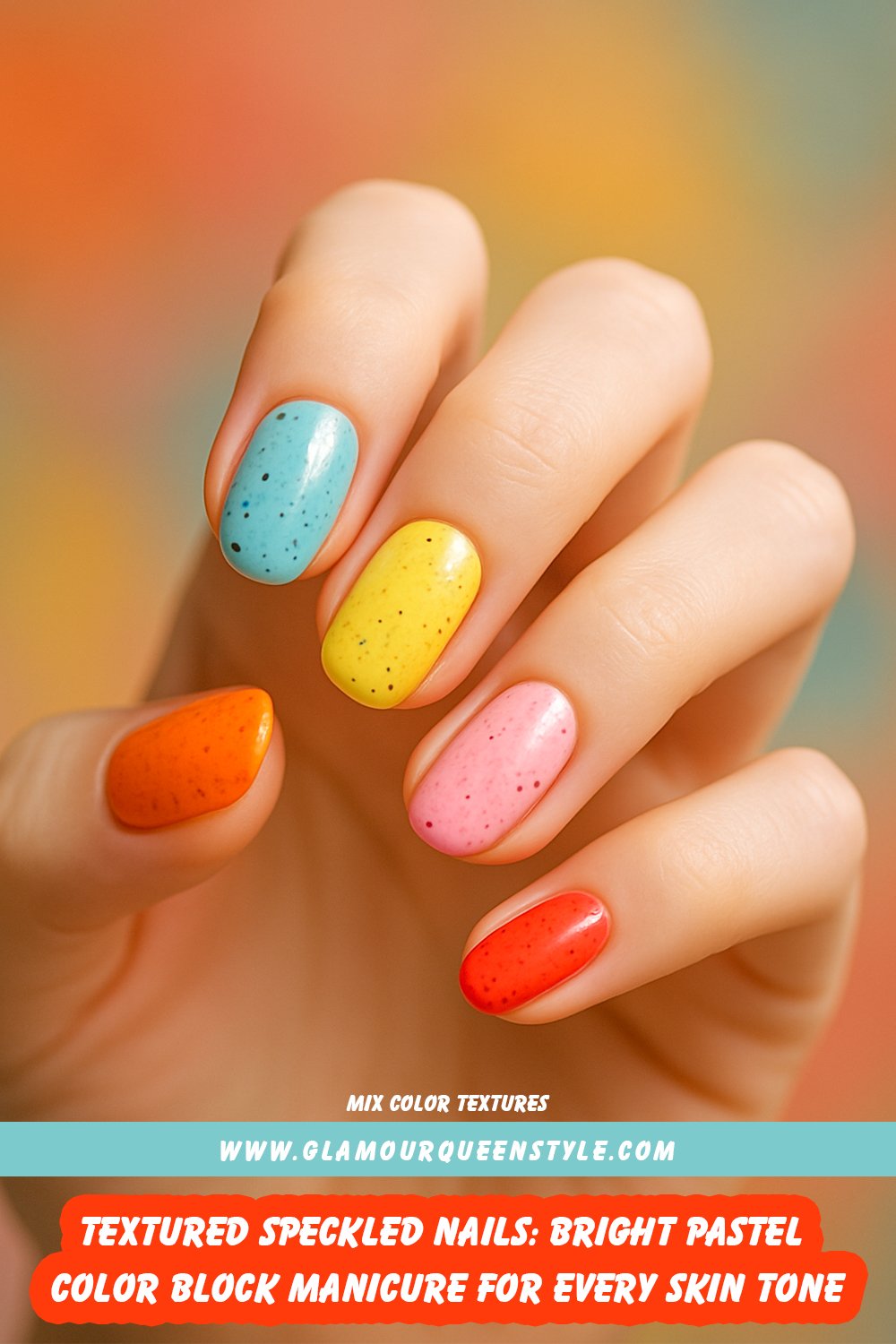Hand with almond-shaped nails painted in bright orange, pastel blue, yellow, pink, and red; each nail has a textured glazed effect featuring tiny black speckles across its surface.